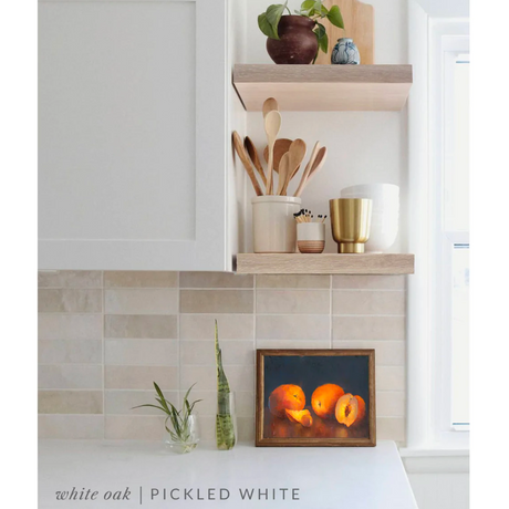 white oak floating shelves in a kitchen with the pickled white finish applied decorated with kitchen utensils, a plant, charcuterie board, and vases